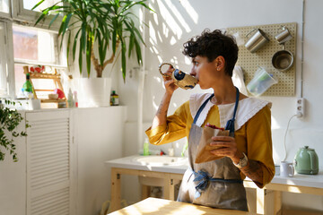 Young girl ceramist drink coffee and has snack in art studio during break from master class or...