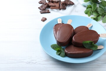 Plate with glazed ice cream bars and fresh mint on white wooden table. Space for text