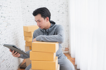 A happy young man with boxes showing thumb-up after packing the package delivered to the customer.