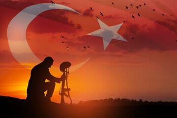 Silhouette of soldier kneeling with his head bowed against the sunrise or sunset and Turkey flag. Concept of crisis of war and conflicts. Greeting card for Turkish Armed Forces Day, Victory Day.