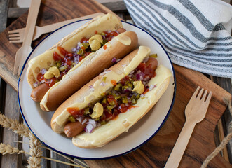 Hot dog with pickles, red onions, cheese, mustard and ketchup