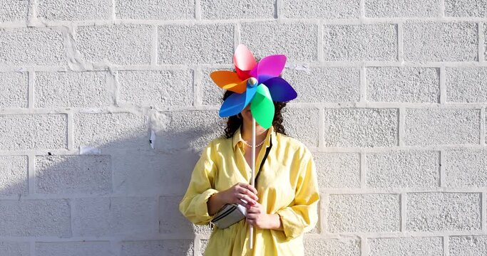 Woman hiding face behind colorful pinwheel