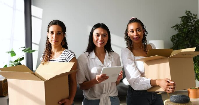 Moving women carrying cardboard boxes friend planning on tablet PC