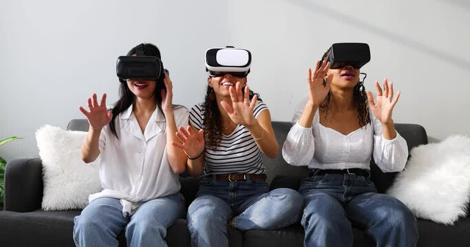 Three girlfriends sitting on couch using virtual reality simulators