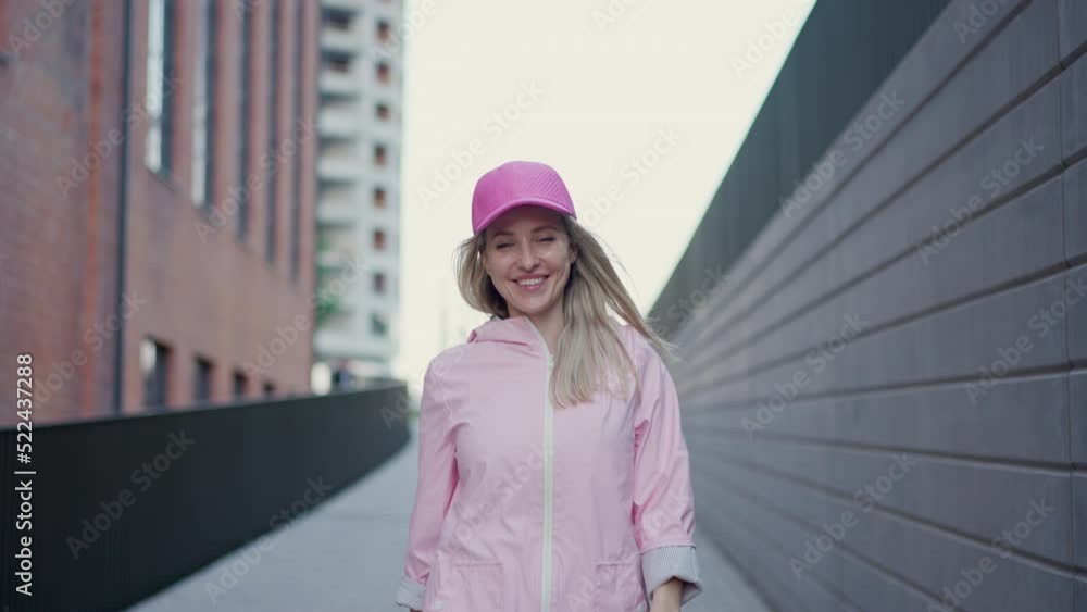 Wall mural Young happy woman in fashion clothes walking in city concrete wall.