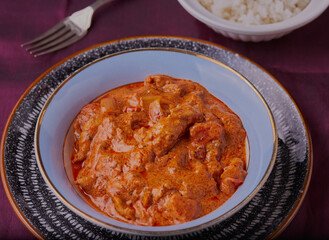Bowl of homemade chicken curry with some rice and chopsticks.