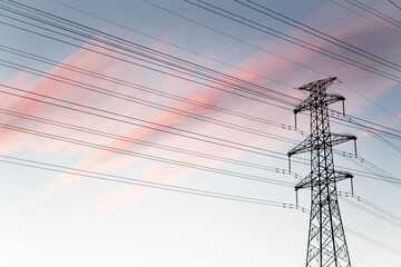 High-voltage lines of communication towers under the burning clouds at sunset
