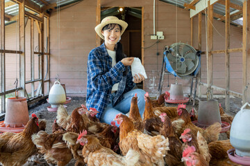 Asian woman farmer is feeding her free range chicken hen house coop which using free range technique © Akarawut