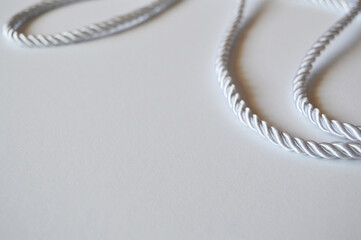 Fototapeta premium White rope cord silky silver textile tie curved lasso line background 