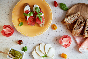 Caprese salad sandwich appetizer with mozzarella, tomatoes, basil leaves and pesto sauce. Italian mediterranean classic recipe. Top view food