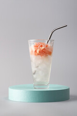 Glass of refreshing cocktail with grapefruit on the podium, still life, advertising photo