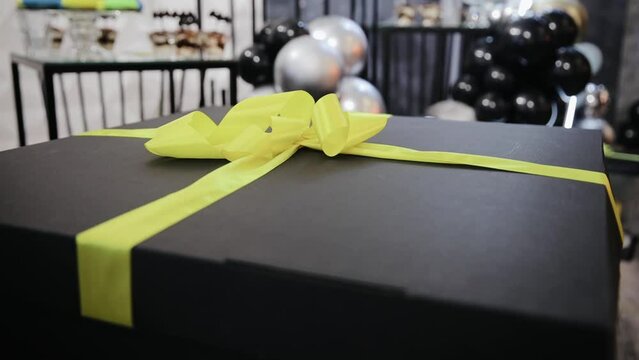 Beautiful big black box with large yellow bow. Celebration of child birthday. Big surprise for the kid bday