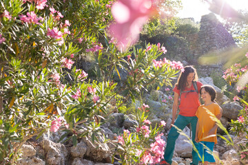 Traveling in Asia, a boy with his mother walks in a beautiful park with oleander flowers
