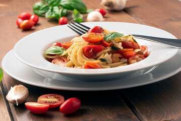 Piatto di deliziosi spaghetti con pomodori pachino, aglio, cipolla, basilico e olio extra vergine...