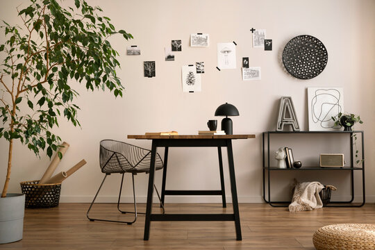 Aesthetic interior of home office interior with design chair, wooden desk, plants, shelf, office accessories, post cards, photos and decoration. Minimalist home decor. Template. 