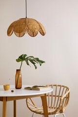Minimalist composition of elegant kitchen space with round table, rattan chair, vase with leaf,...