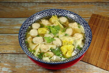 Traditional hot wonton soup mixed with pork ball serving in the bowl. Famous soft and light menu in Chinese restaurant. 