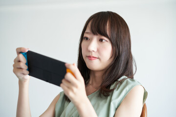 携帯型のゲーム機で遊ぶ女性