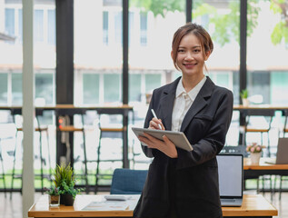 Obraz premium marketing, finance, accounting, planning, businesswoman holding a tablet Analyze company results and profits with graph statistics. Use a laptop and a calculator to calculate your company balance.