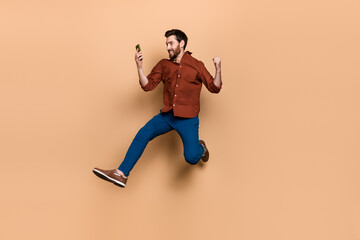 Fototapeta na wymiar Full size photo of overjoyed satisfied guy jumping raise fist celebrate like subscribe isolated on beige color background