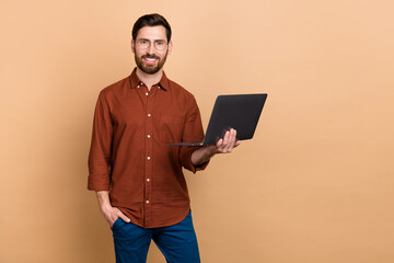 Photo of cheerful intelligent person hold wireless netbook toothy smile isolated on beige color background