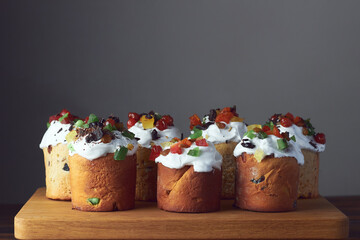 Several Kulich. Traditional easter cakes, bread with meringue and colorful sprinkles and candied fruit on wooden board and gray background
