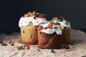 Three homemade raditional Russian and Ukrainian Easter cake kulich or bread kulich decorated with candied fruit on rustic wooden table and paper. Happy Easter holiday