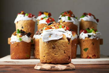 Several traditional easter cakes kulich (orthodox ukraniane culture) lined up like a choir on wooden board against grey wall