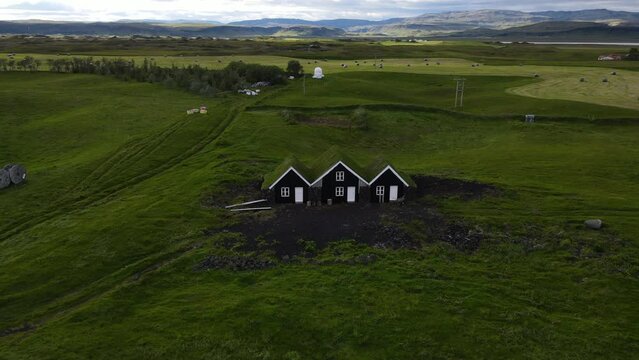 Aerial view of turf house in Island. Iconic small Iceland's house surrounded by green field.