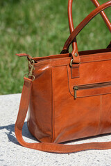 close-up part photo of orange leather bag on a white marble