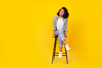 Full length photo of cute young lady wavy hair sit stool look empty space dressed stylish khaki...