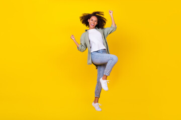 Fototapeta na wymiar Full size photo of cute young woman wavy hair raise fists celebrate success dressed stylish khaki look isolated on yellow color background