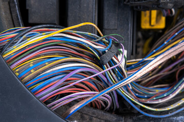 A bundle of electrical wires or cables is strongly mixed up with each other. Remnants of wires of...