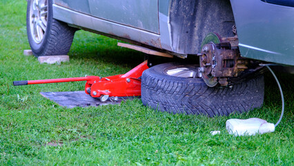 Fototapeta premium the car is raised on a red jack