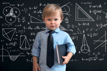 a smart boy in a school uniform, standing at the blackboard with mathematical signs, graphs and...