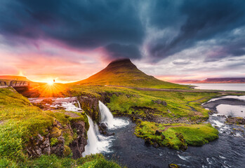 Landscape of sunset over Kirkjufell mountain with Kirkjufellsfoss waterfall and colorful pileus cloud on summer at Iceland
