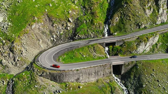 Aerial drone view of nature in Romania. Transfagarasan route in Carpathian mountains with moving cars, rocky slopes with greenery