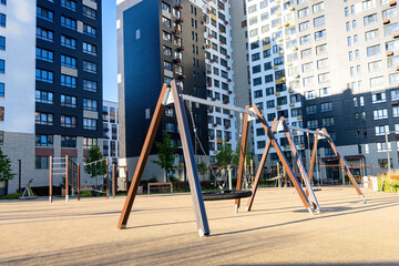 Empty metal chain swings on the empty kids children  playground courtyard of the residential district