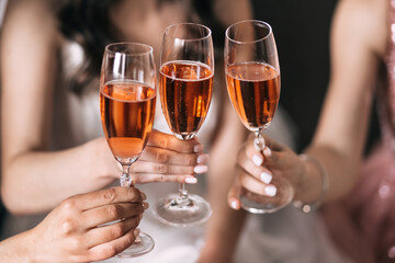 Bride with best bridesmaids are holding glasses and drinking champagne in hotel.