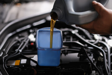 Fototapeta na wymiar Pour gear oil into car through watering can