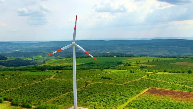 A working windmill in a field. Cloody weather, a lot of greenery around it