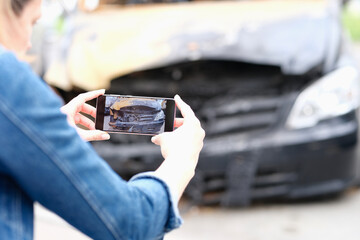 Person photographs burnt car on smartphone closeup - obrazy, fototapety, plakaty