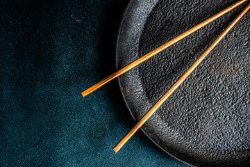 Overhead view of a pair of chopsticks on a metal plate