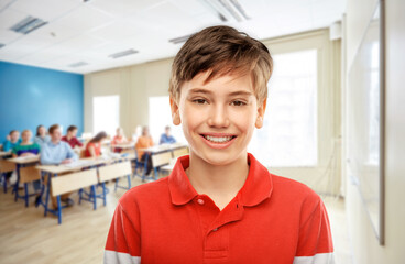 education, school and people concept - portrait of happy smiling student boy in red polo t-shirt over classroom background