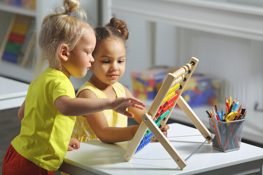 children of different races sit together at the table and count on the abacus
