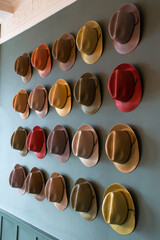 Colourful trilby hat collection, displayed on a wall. A multi coloured  selection of Trilby hats also known as the Fedora hat, as worn by Frank Sinatra. selective focus. Bright colourful display - obrazy, fototapety, plakaty
