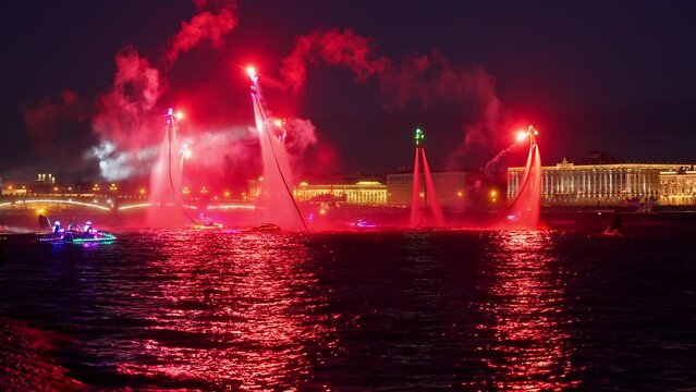 A lot of flyboarders and brightly dressed up jet skiers perform their show at a holiday in the center of St. Petersburg at night, water activities