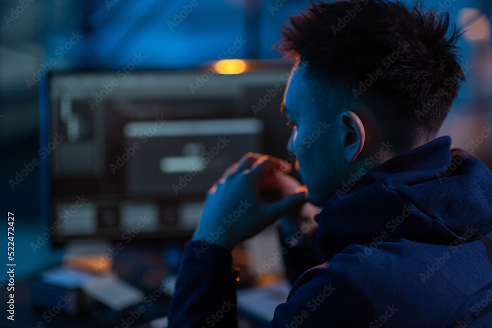 Poster cybercrime, hacking and technology concept - close up of male hacker in dark room using computer vir