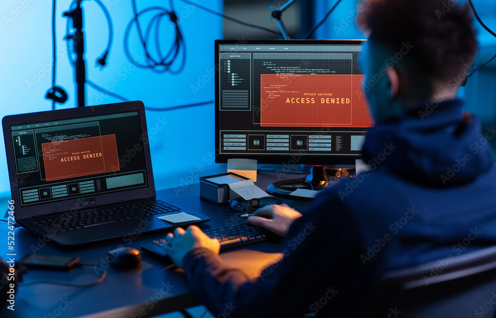 Poster cybercrime, hacking and technology concept - male hacker in dark room writing code or using computer