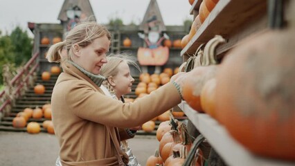 Mom and daughter buy pumpkins at the Halloween and Thanksgiving fair
